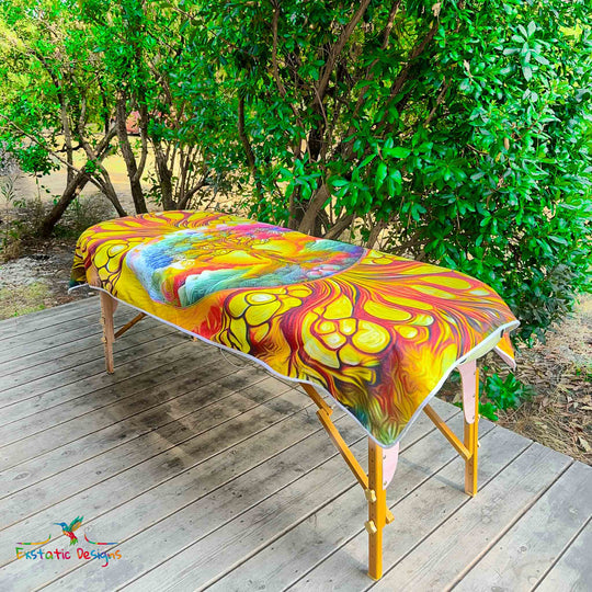 Serviette géante Tantra & Massage "Homme Racine" posée sur une table de massage en extérieur, vue complète, motifs vibratoires d’ancrage et de racines reliant à la nature primordiale, création vibratoire signée Xavier Gaillot pour Exstatic Designs.
