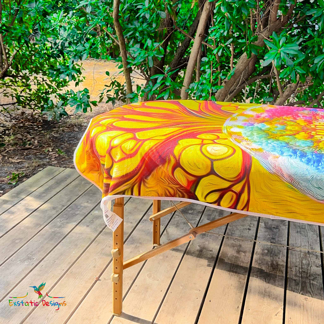 Détail de la serviette géante Tantra & Massage "Homme Racine" sur une table de massage en extérieur, vue rapprochée d’une extrémité avec motifs enracinés symbolisant force intérieure et lien à la Terre, création vibratoire signée Xavier Gaillot pour Exstatic Designs.