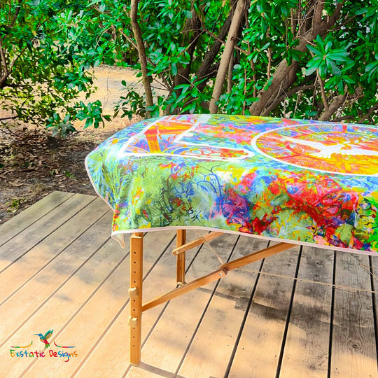 Détail de la serviette géante Tantra & Massage "Jungle d’Amour" sur une table de massage en extérieur, vue rapprochée du LOVE vertical, de la colombe et des motifs de jungle, création vibratoire de Xavier Gaillot.