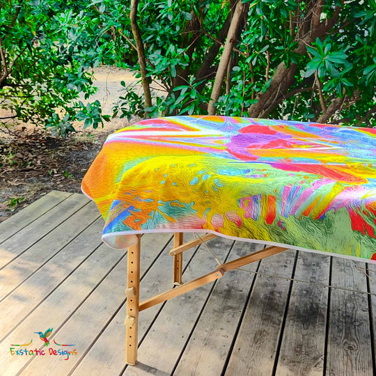 Détail de la serviette géante Tantra & Massage "Feu extatique" sur une table de massage en extérieur, vue rapprochée des flammes sacrées et des couleurs ardentes, création vibratoire de Xavier Gaillot.