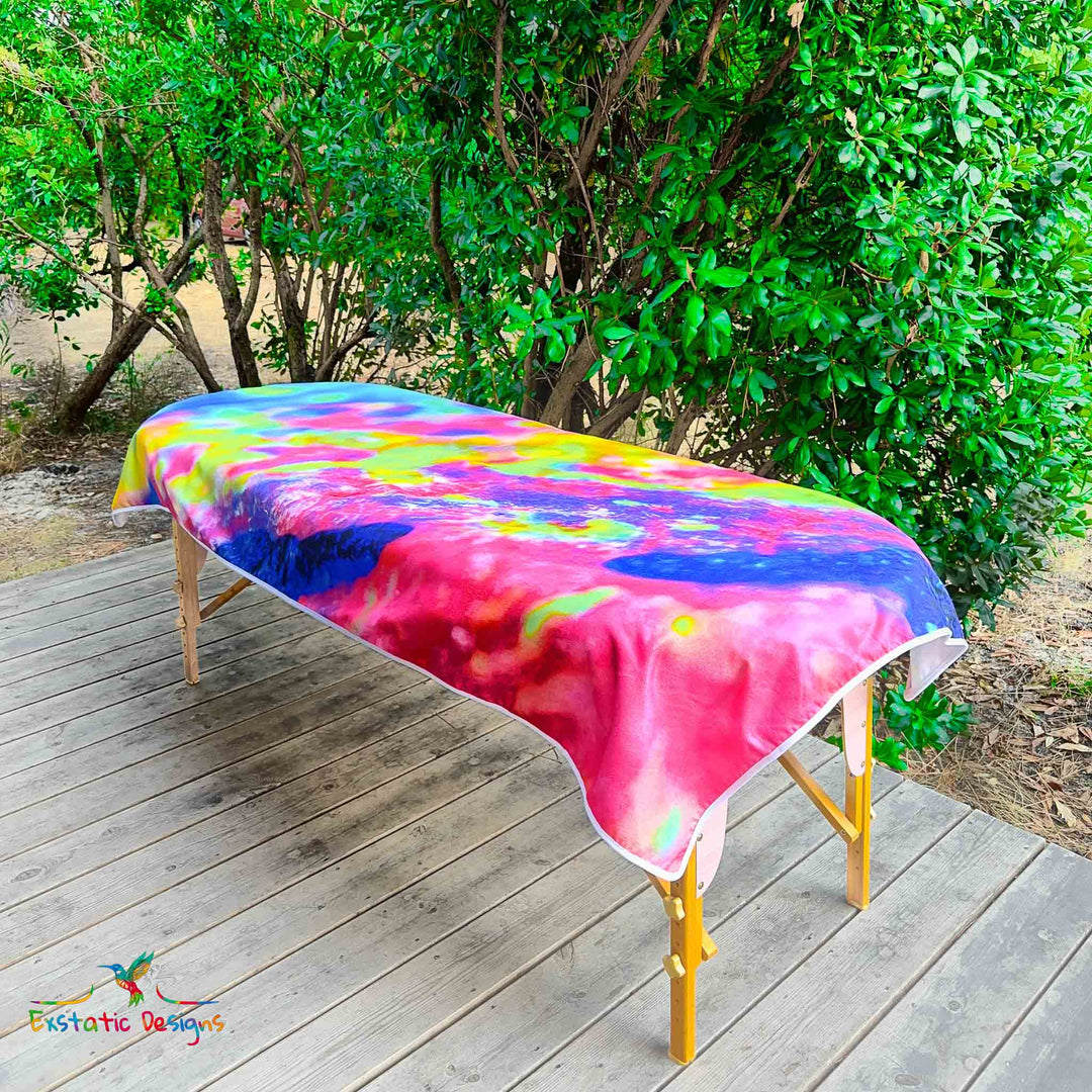 Serviette géante Tantra & Massage "Transe Minérale" posée sur une table de massage en extérieur, vue complète, textures minérales et couleurs arc-en-ciel, création vibratoire de Xavier Gaillot pour Exstatic Designs.
